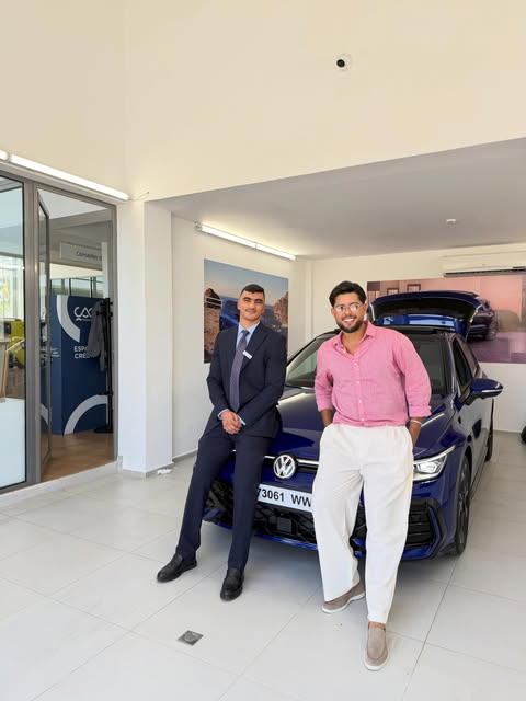 Anas Karmoun et un client devant une Golf bleue en showroom