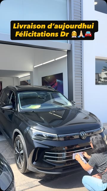 Livraison d'un Tiguan noir devant le showroom